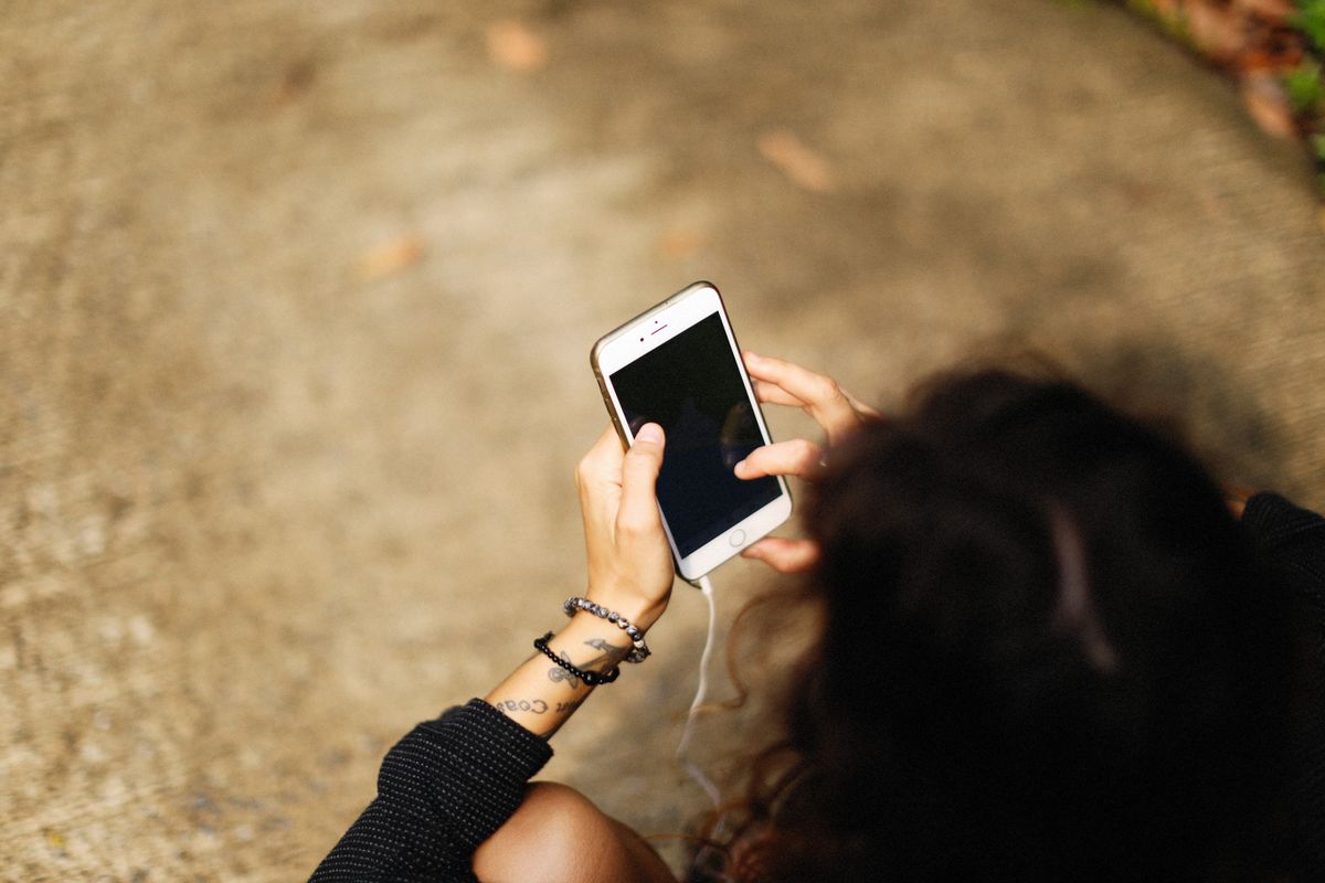 Mujer con su teléfono en la mano al aire libre, revisando los ajustes del teléfono
