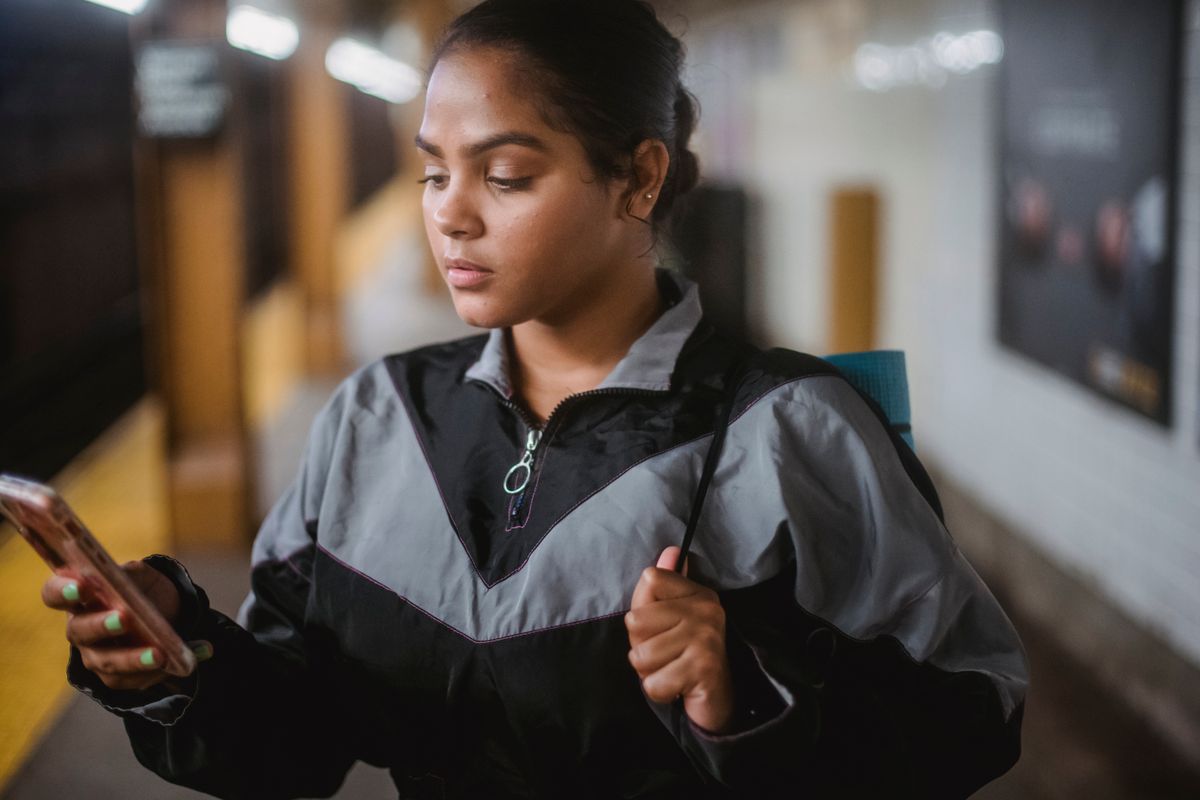 Young traveller with a backpack checking her phone on a subway platform