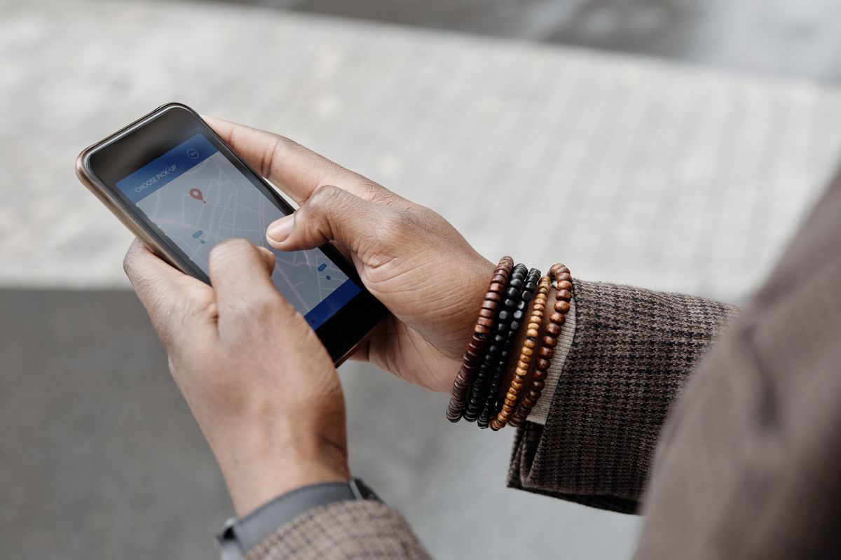 Mani che tengono uno smartphone con una mappa aperta in una via della città