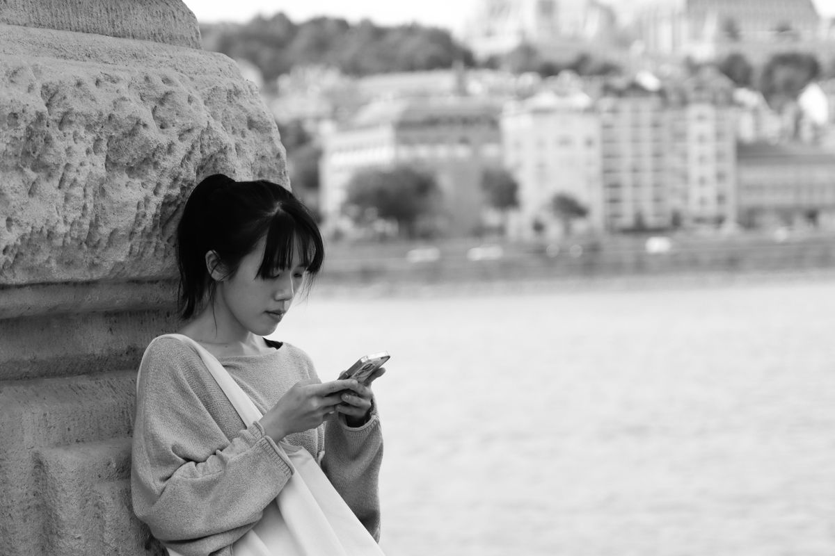 Young woman checking her phone by the Danube in Budapest
