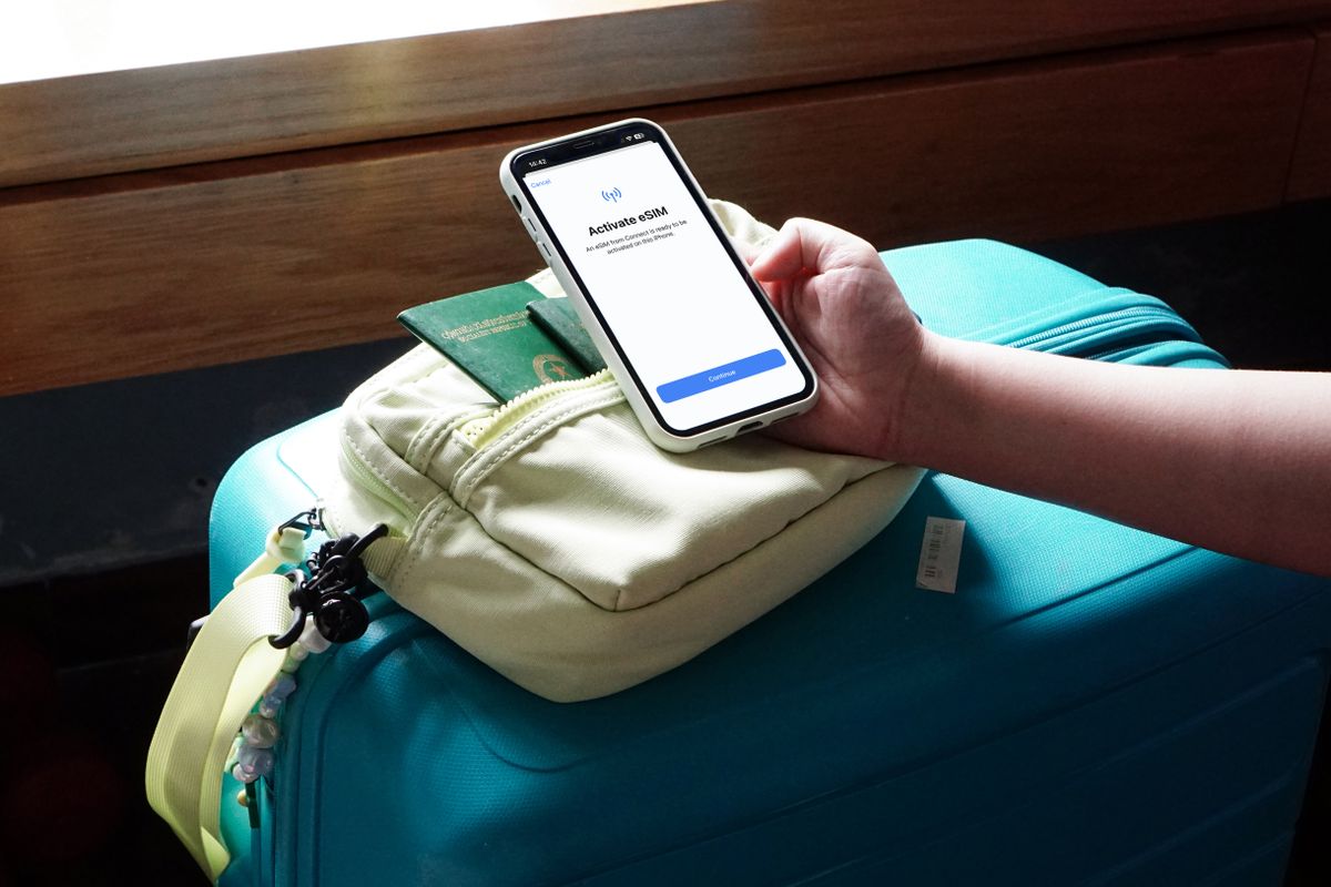 Reisende aktiviert über ihrem Koffer eine eSIM auf dem Handy