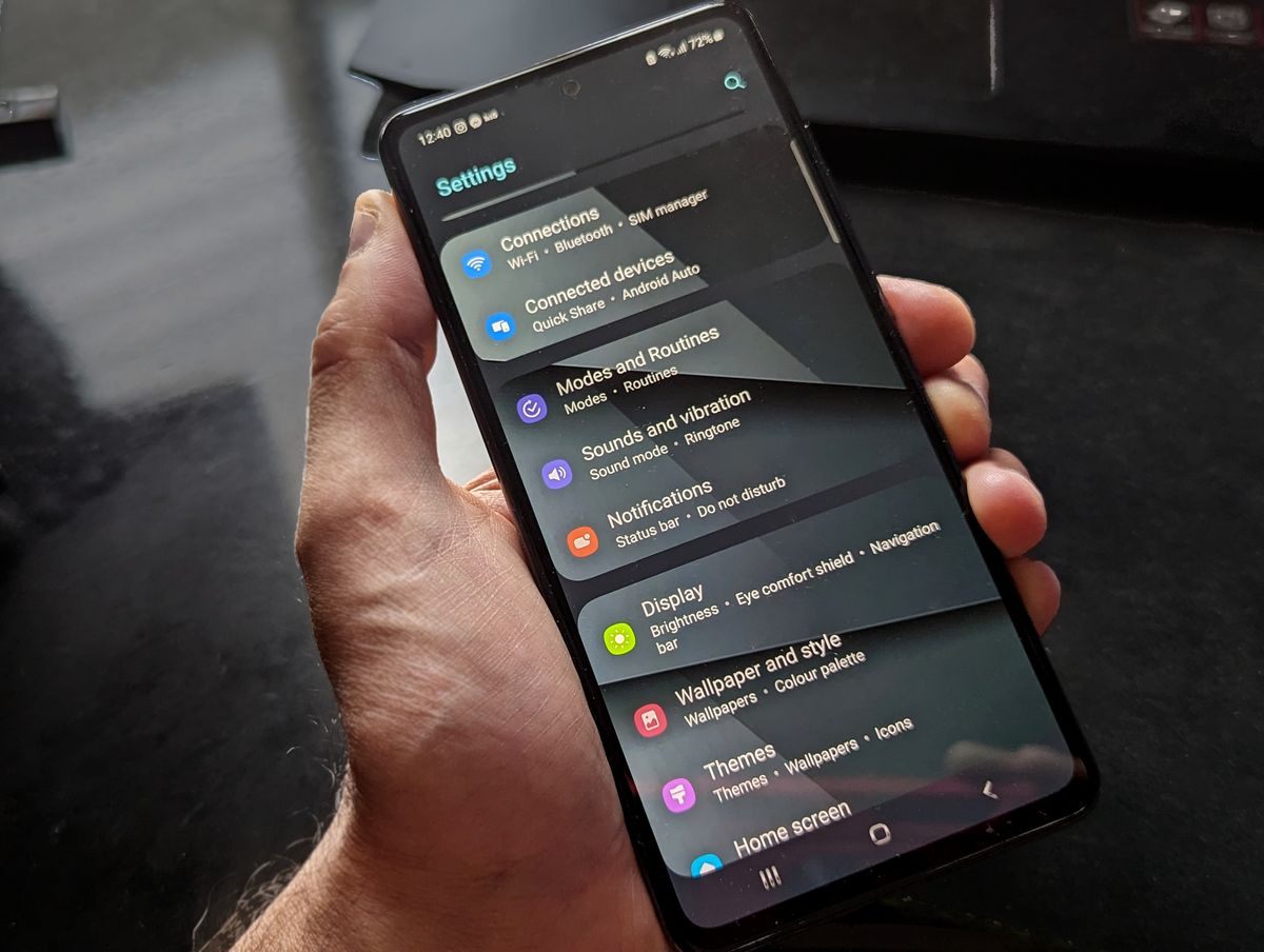 Mano sosteniendo un teléfono Android con la pantalla de Ajustes abierta