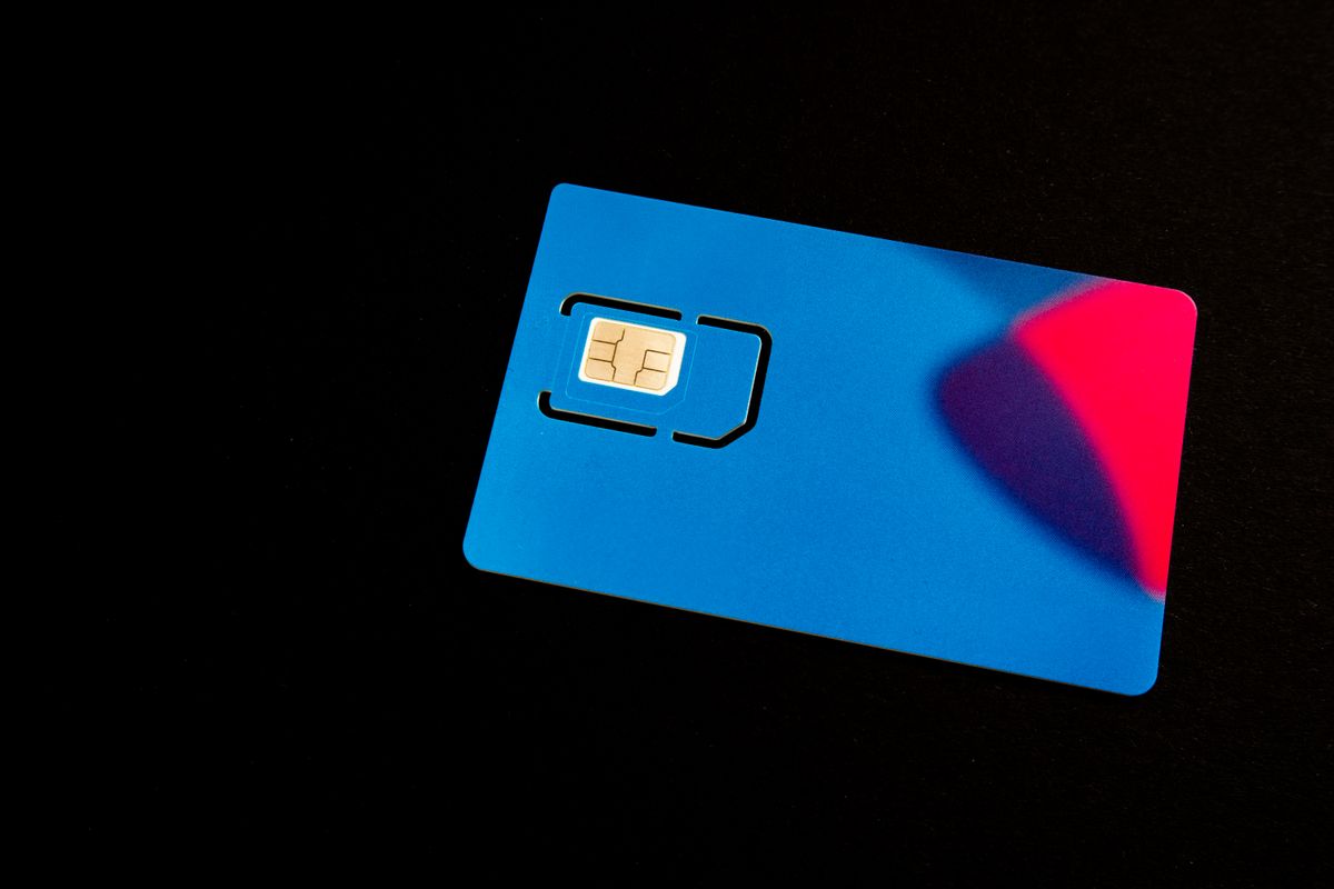 Supporto di una SIM fisica blu con chip dorato su sfondo scuro