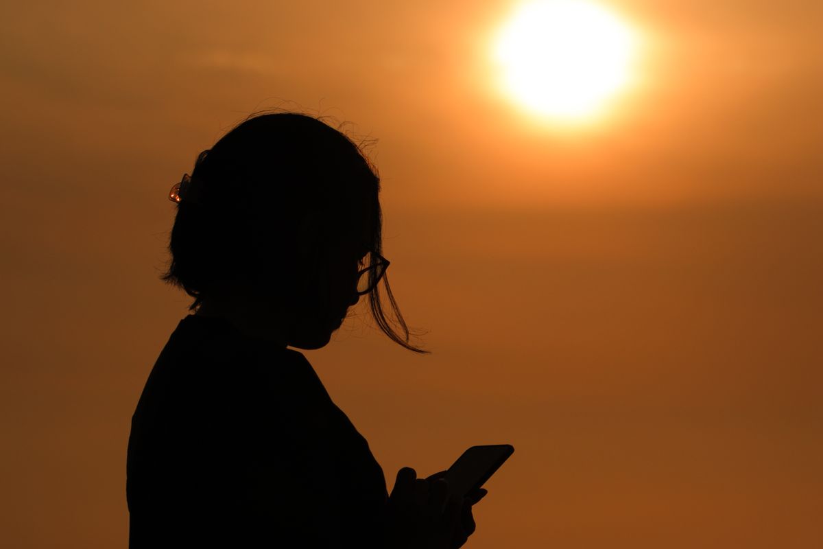 Mujer mirando su smartphone al atardecer en Barranco, Lima