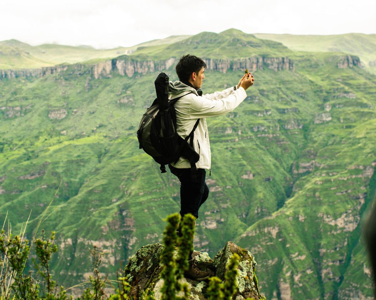 Excursionista haciendo una foto con su teléfono sobre un valle andino verde cerca de Cusco, Perú
