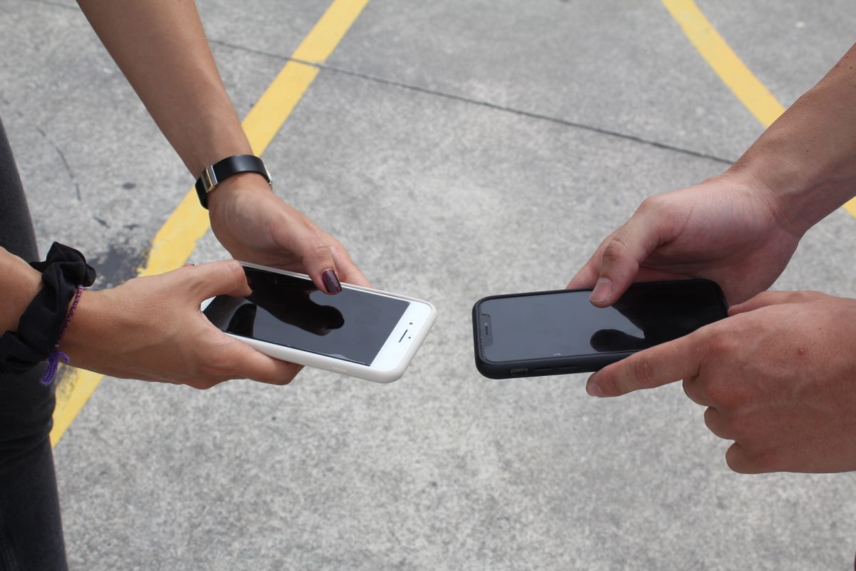Duas pessoas ao ar livre com os smartphones lado a lado