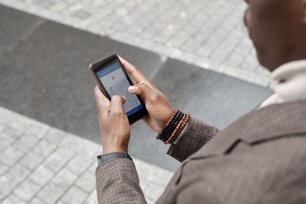 Traveller checking a map app on his smartphone on a paved city street