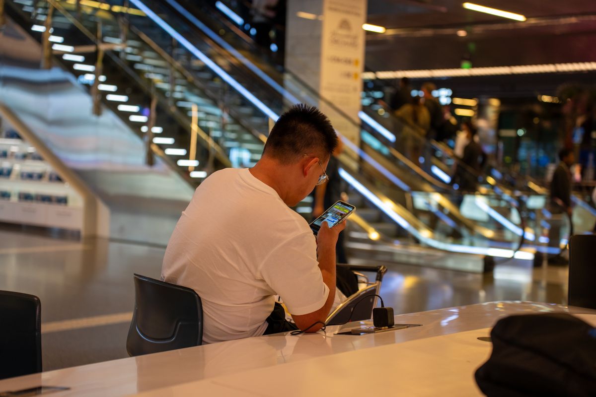Voyageur qui utilise son smartphone à une table dans un terminal d'aéroport