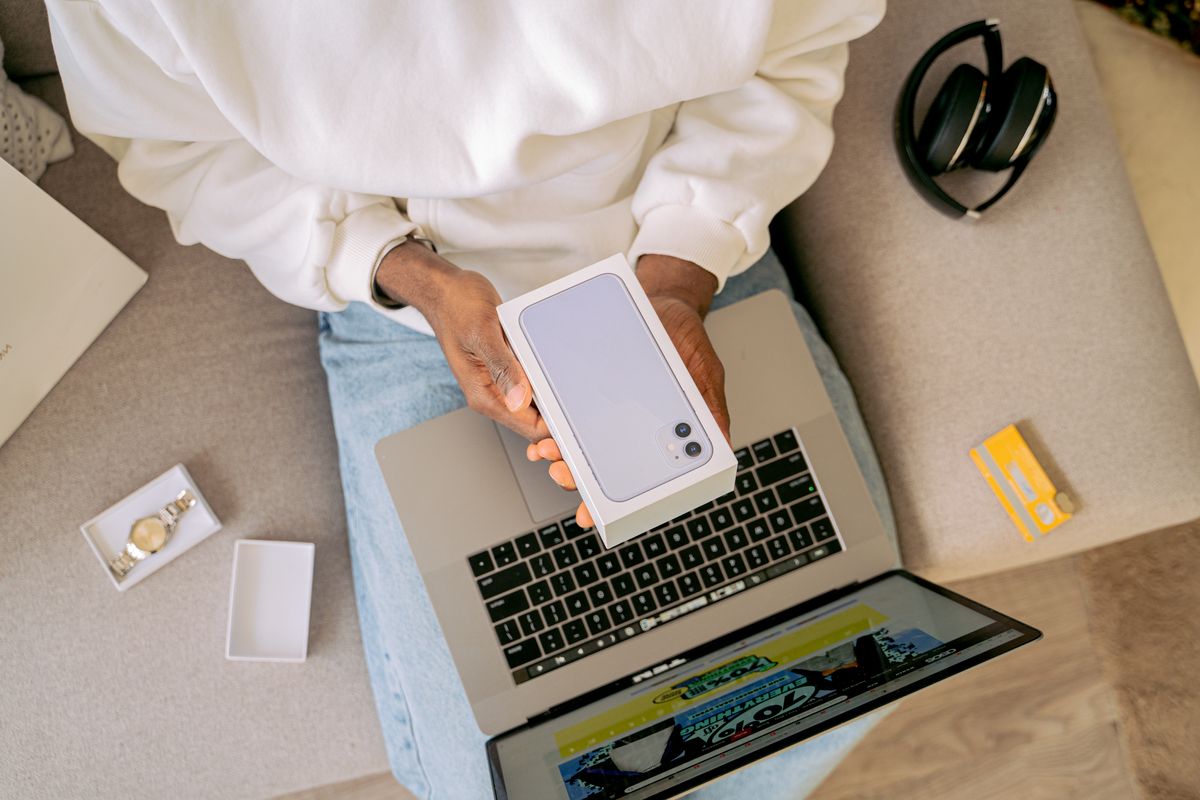 Persona con la caja de un smartphone nuevo sobre una laptop después de comprar un celular en línea