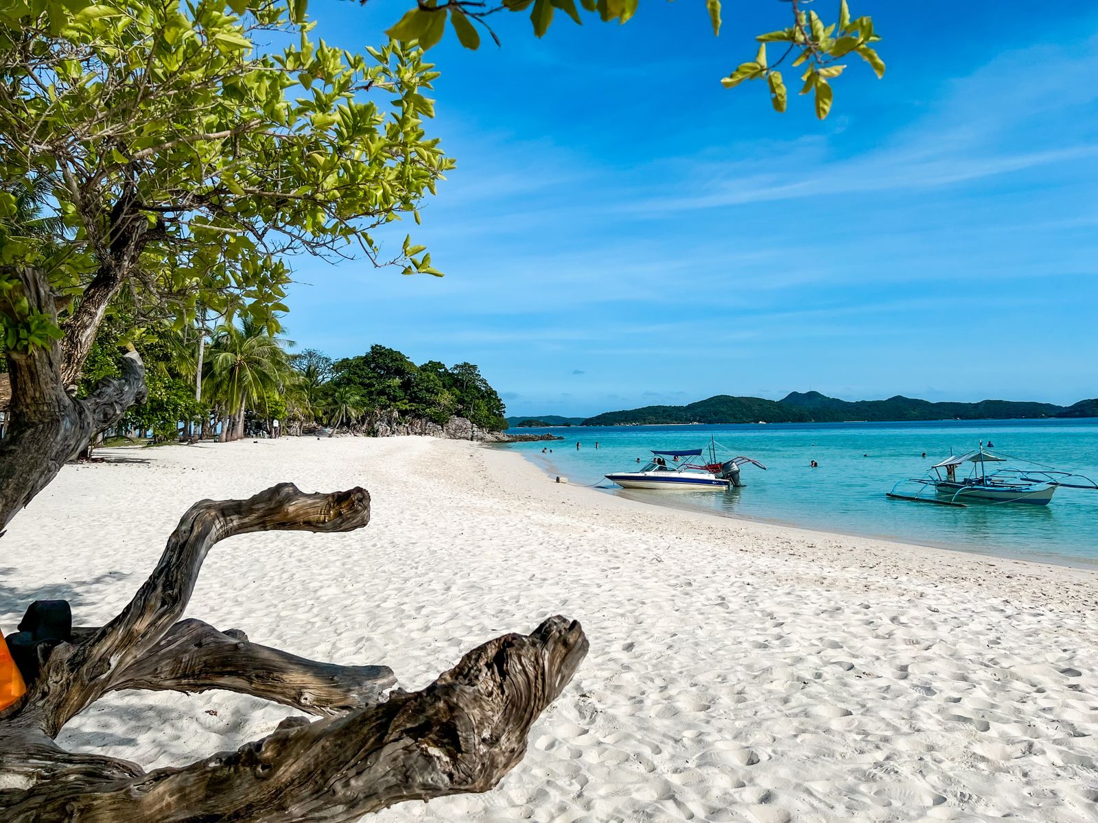 Barcas en una playa de arena con agua cristalina en Palawan